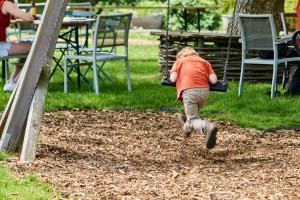 Ein kleines Kind rennt auf einem Spielplatz eine Rutsche hinunter. in der Unterkunft De Pastorie in Borgloon