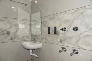 a white bathroom with a sink and a mirror at D D Luxury Inn in Chikmagalūr