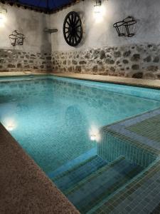 a large swimming pool with blue water and a wheel at Casa Rural Abuelo Pedro in Cuerva