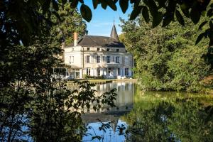 an old house reflected in the water of a lake at CHATEAU Les VALLÉES in La Roche-Posay