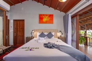 a bedroom with a large white bed with flowers on it at Hoianbang Beach Front Villa and Restaurant in An Bàn (2) +20 photos