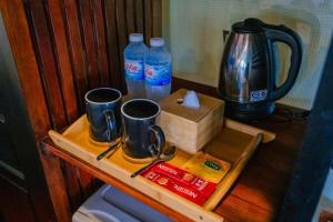 a table with two coffee mugs and a box of water at Hoianbang Beach Front Villa and Restaurant in An Bàn (2)