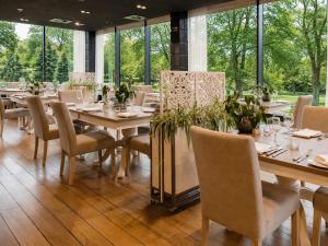 a dining room with tables and chairs and windows at Herbarium Hotel & Spa in Gąsawa