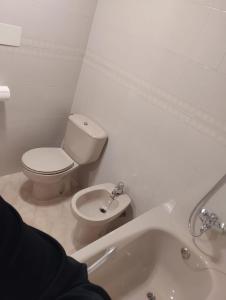 a white bathroom with a toilet and a sink at Eclipse in Olvega