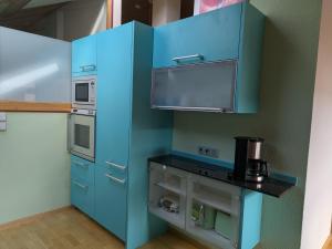 a kitchen with blue cabinets and a microwave at FEWO Villa Farbenfroh Monteurzimmer Garten Wlan 3SZ 120qm in Wathlingen