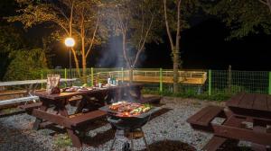a barbecue grill and picnic tables in a park at night at Gapyeong Elin Pension in Gapyeong