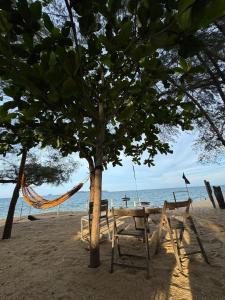 a picnic table and a hammock on a beach at Beach hut cabin in Marang