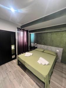 a bedroom with a green bed with towels on it at Affittacamere Plaza in Pietracatella