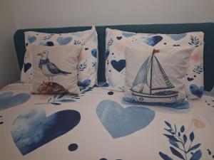 a bed with two pillows with a sailboat on it at Sunshine- self sheck in in Čačak