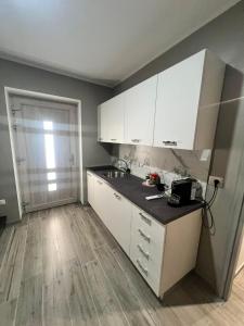 a kitchen with white cabinets and a black counter top at Affittacamere Plaza in Pietracatella