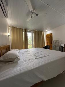 a large white bed in a bedroom with a ceiling fan at Tangerine House in Canacona