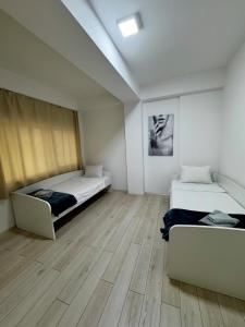 a room with two beds and a wooden floor at Neptun Apartments in Gevgelija