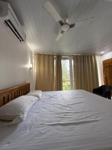 a bedroom with a white bed with a ceiling fan at Tangerine House in Canacona
