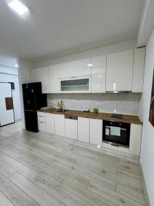 a kitchen with white cabinets and a black refrigerator at Neptun Apartments in Gevgelija