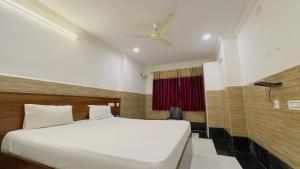 a bedroom with a white bed and a red window at Tirupati Stays in Tirupati