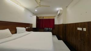 a bedroom with a white bed and a red curtain at Tirupati Stays in Tirupati