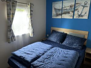 a bed with blue sheets in a bedroom with a window at Beach Resort Kamperland - 1152 in Kamperland