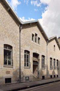 a white brick building with windows on a street at La Maison Générale in Besançon