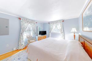 a bedroom with a large white bed and two windows at The Sea Captain's Sanctuary in Ocean City