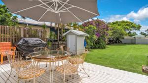 a patio with a table and chairs and an umbrella at Bruns Beach Shack in Brunswick Heads