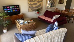a living room with couches and a flat screen tv at Ahoy Brunswick 1 in Brunswick Heads