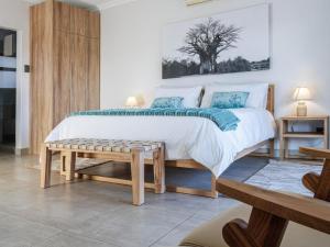 a bedroom with a large bed with a bench next to it at Thaba Tshwene Game Lodge in Hartbeesfontein +21 photos