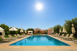 a swimming pool with lounge chairs and umbrellas at Palais Zoya in Marrakesh