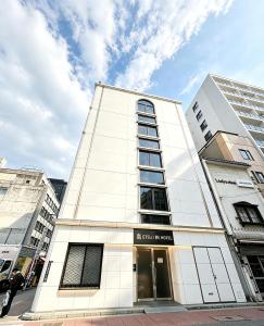 a tall white building with a sign on it at ETSU 悦 HOTEL Chuo Ward Tokyo 1-2BDR House in Tokyo