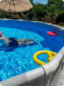 Eine Person schwimmt mit einem Sonnenschirm in einem Schwimmbecken in der Unterkunft villa Rodo in Platanidia