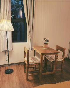 a wooden table and chairs with a lamp and a window at Monoi Home in Vinh