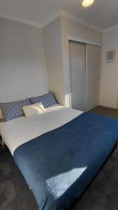 a bedroom with a large bed with a blue blanket on it at Private Flat in Bridge Hill in Alexandra +20 photos