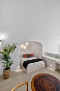 a white bedroom with a bed and a potted plant at You and Me Suites Oia in Oia +80 photos