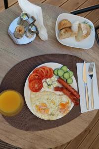 a table with a plate of food with eggs sausage and vegetables at Oribu Boutique Hotel Vlore in Vlorë