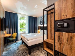 a hotel room with a bed and a desk at ibis Styles Hamburg Barmbek in Hamburg +105 photos