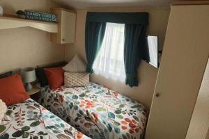 a small bedroom with a bed and a window at 2 Bedroom Caravan - Sleeps 6 - Parking Seaside in Abergele