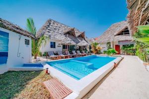 a swimming pool in front of a house at King Simba Apartment Hotel & Restaurant in Bwejuu