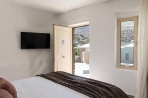 a bedroom with a bed with a television and a window at Domotel Kea in Koundouros