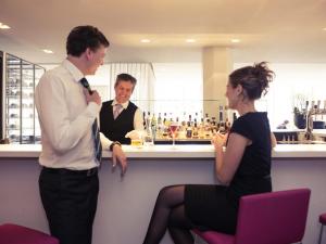 two men and a woman standing at a bar at Mercure Hotel Nijmegen Centre in Nijmegen