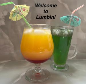 two drinks sitting on a table with an umbrella at LUMBINI B&b in Kandy