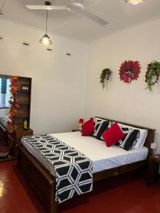 a bedroom with a bed with red and black pillows at LUMBINI B&b in Kandy