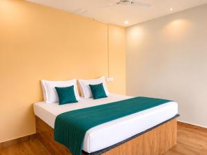 a bedroom with a large bed with green and white pillows at Royal Shouryas Resort in Kolhapur