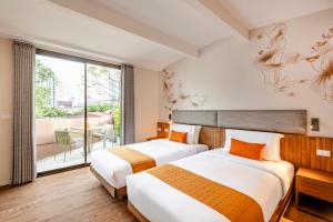 two beds in a hotel room with a balcony at Taladnoi 24 Hostel in Bangkok