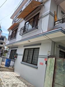 a white house with black windows and a sidewalk at Aangan Homestay in Pātan