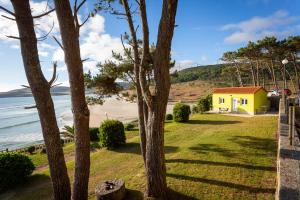 a yellow house on the beach next to the ocean at Apartamento Playa de Lires in Cee