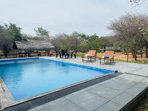 a swimming pool with two chairs and a table at Thihawa Yala in Tissamaharama