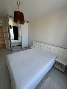 a bedroom with a white bed and a mirror at Panorama Apartment in Lviv
