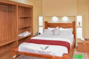 a bedroom with a large bed with a wooden headboard at Paneah hotel and suites in Nairobi