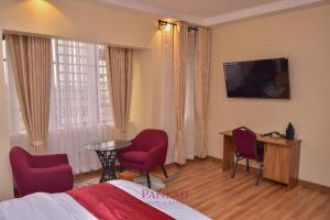 a hotel room with a bed and a table and chairs at Paneah hotel and suites in Nairobi