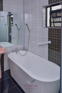 a white bath tub in a bathroom with a window at Paneah hotel and suites in Nairobi +1 photo
