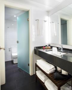 ein Badezimmer mit einem Waschbecken, einem WC und einem Spiegel in der Unterkunft Durlet Beach Apartments in Barcelona